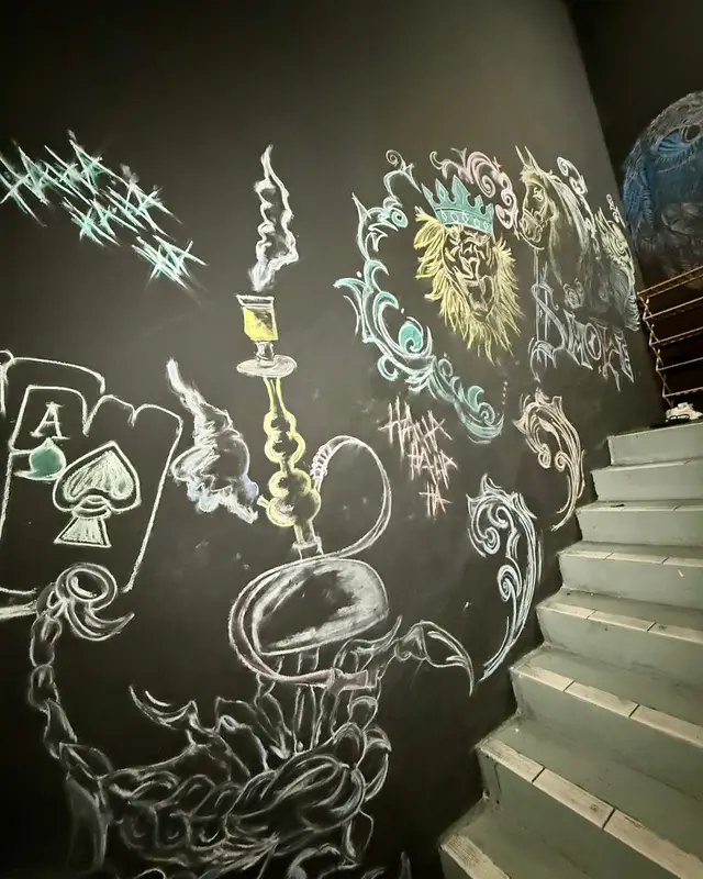 Chalk drawings of a shisha and playing cards on the wall beside the stairs.