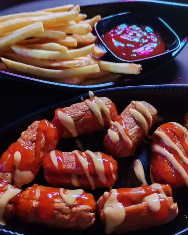 Fries with a dip, and sausages topped with two sauces.