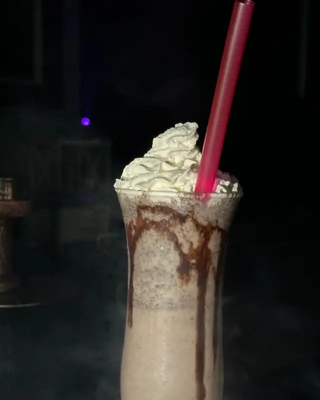 A milkshake with whipped cream and chocolate sauce.