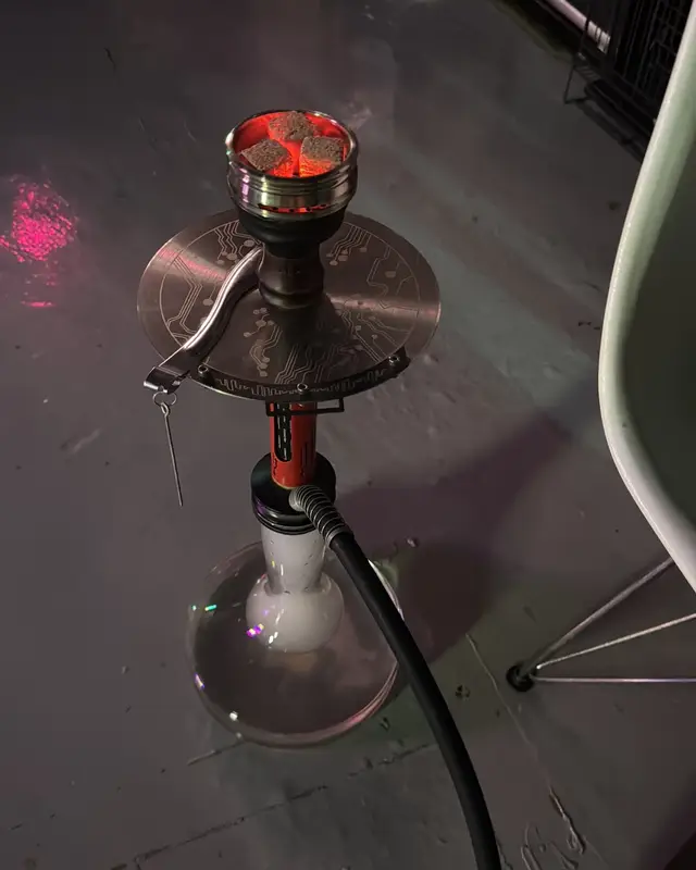 A shisha with glowing coals in its bowl.