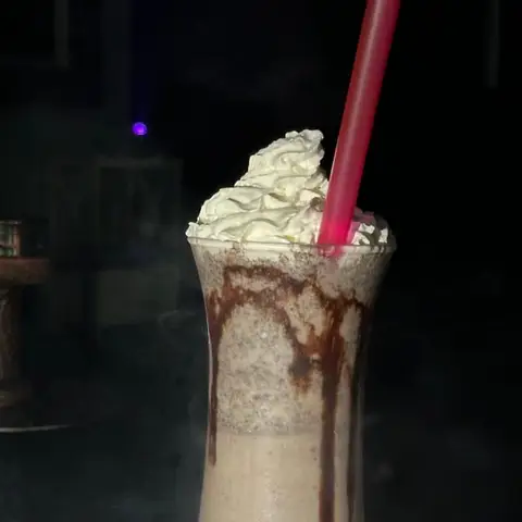 A milkshake with whipped cream and chocolate sauce.