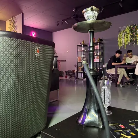 A shisha in front, with guests at a table behind.